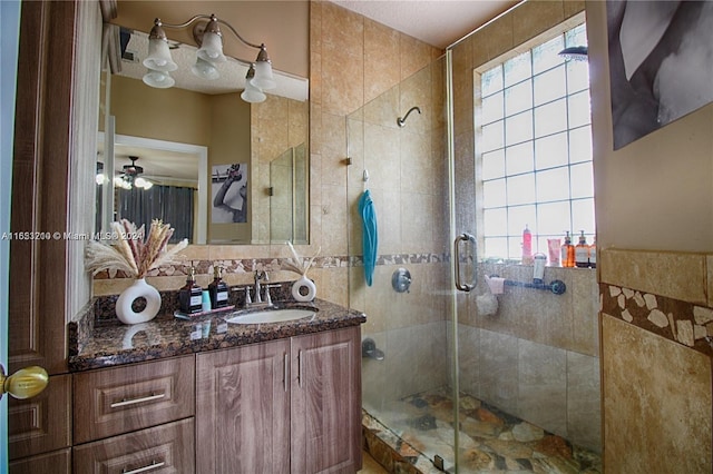 bathroom featuring vanity, tile walls, a healthy amount of sunlight, and walk in shower