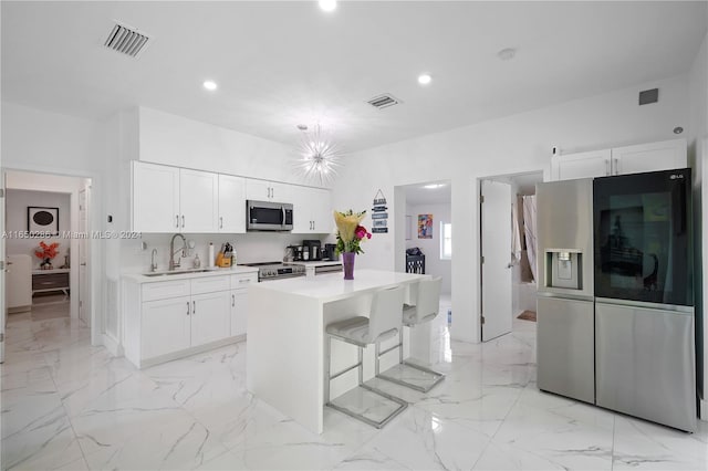 kitchen featuring stainless steel appliances, sink, white cabinetry, and a center island