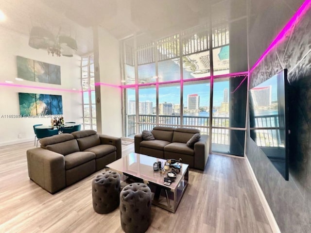 living area featuring a view of city, wood finished floors, a towering ceiling, and baseboards