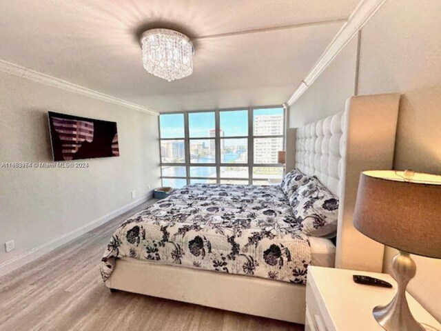 bedroom featuring crown molding, hardwood / wood-style floors, and a chandelier