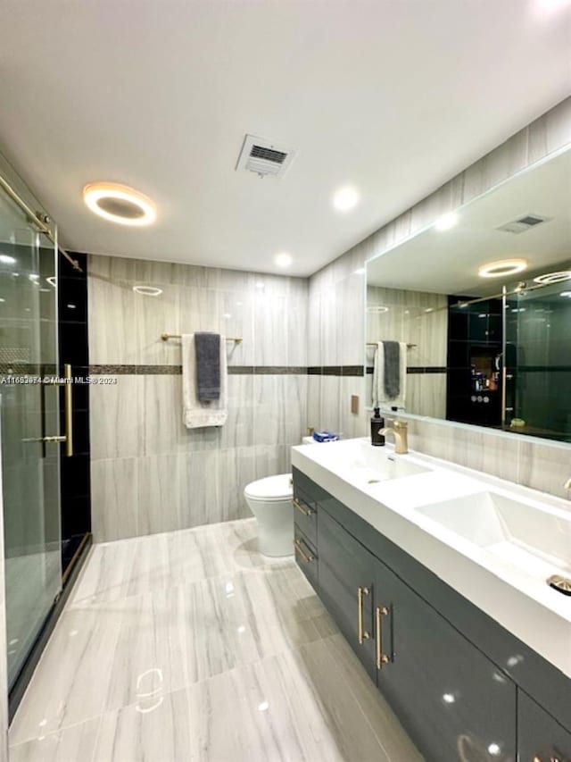 bathroom with vanity, toilet, walk in shower, and tile walls