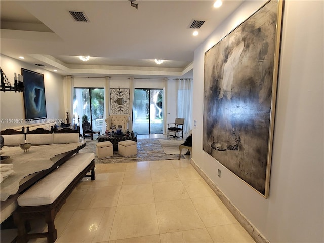 corridor with light tile patterned flooring and a tray ceiling