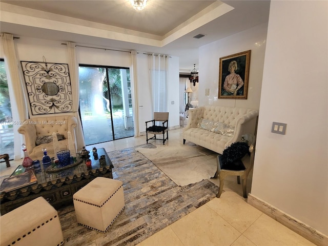 living area with a tray ceiling and light tile patterned floors