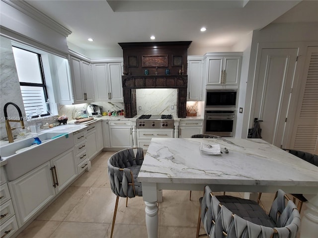 kitchen with a breakfast bar, stainless steel microwave, decorative backsplash, light stone countertops, and white cabinetry