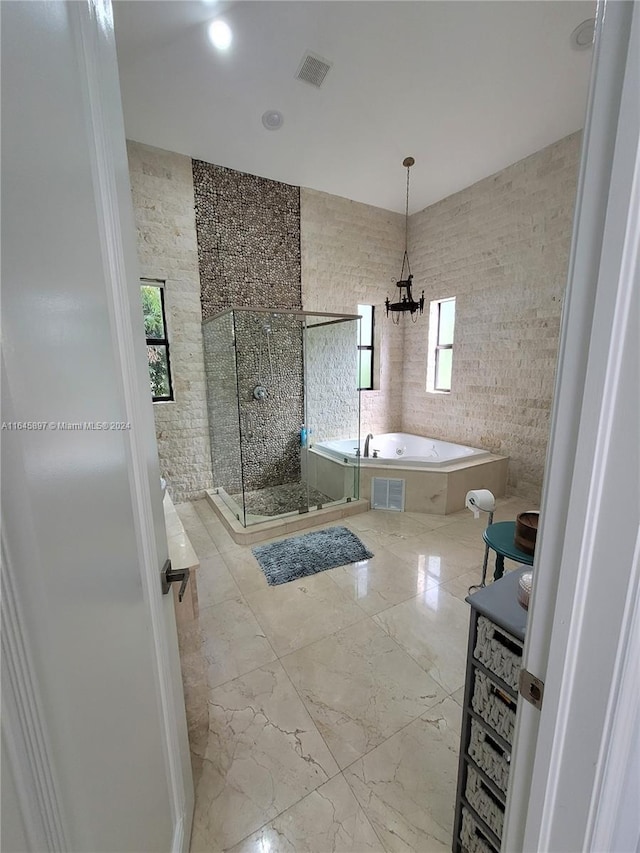 bathroom featuring separate shower and tub, tile walls, and an inviting chandelier