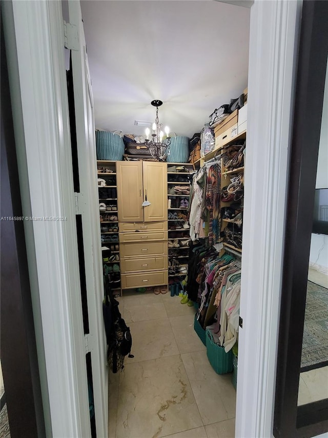 walk in closet with a notable chandelier