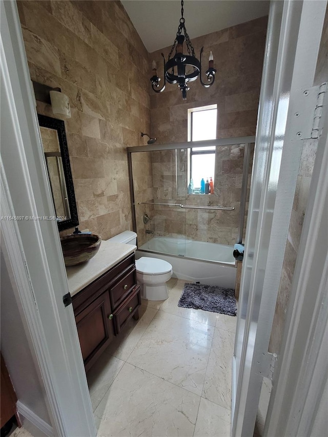 full bathroom with toilet, a notable chandelier, shower / bath combination with glass door, tile walls, and vanity