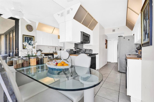 tiled dining area featuring ceiling fan and vaulted ceiling