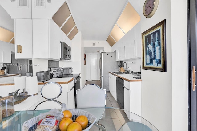 kitchen with stainless steel appliances, white cabinets, and light tile patterned flooring