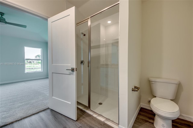 bathroom with a shower with shower door, toilet, ceiling fan, and hardwood / wood-style flooring