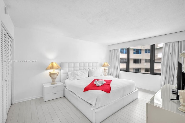 bedroom featuring light hardwood / wood-style floors and a textured ceiling