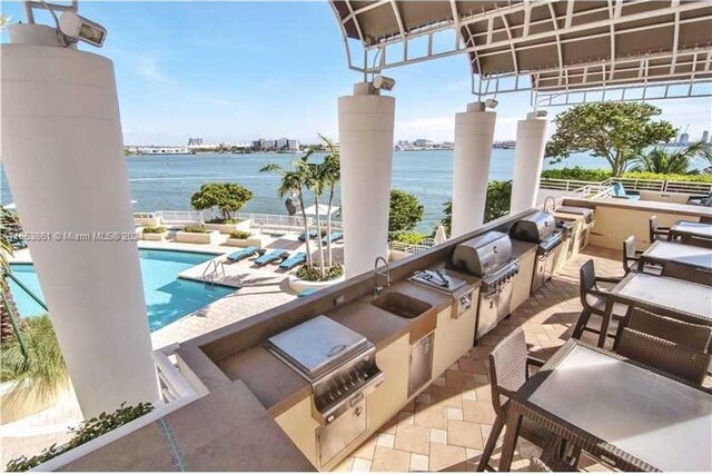 808 Brickell Key Dr Unit 2005, Miami, FL 33131 - view of patio / terrace with an outdoor kitchen, a water view, and a community pool