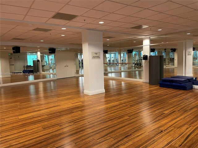 workout area featuring a paneled ceiling and wood-type flooring