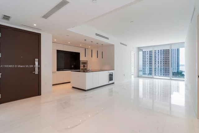 kitchen featuring white cabinets, a center island, sink, and floor to ceiling windows