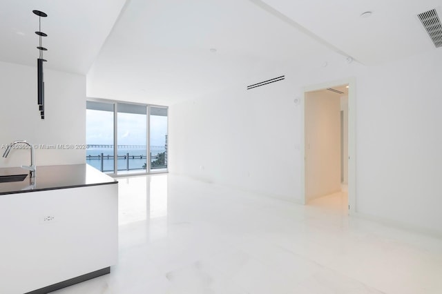 kitchen featuring a water view, a wall of windows, and sink