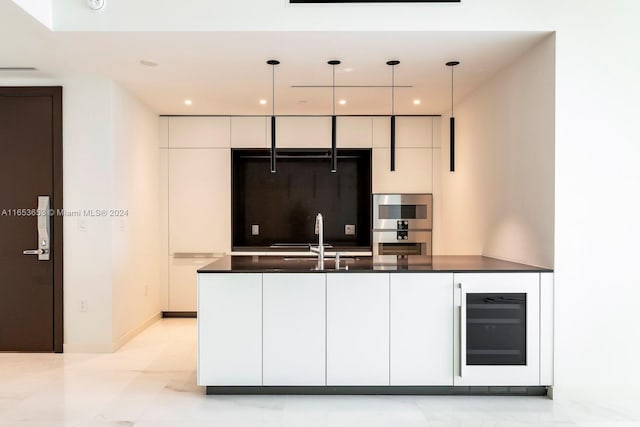 kitchen with pendant lighting, white cabinets, sink, beverage cooler, and stainless steel double oven