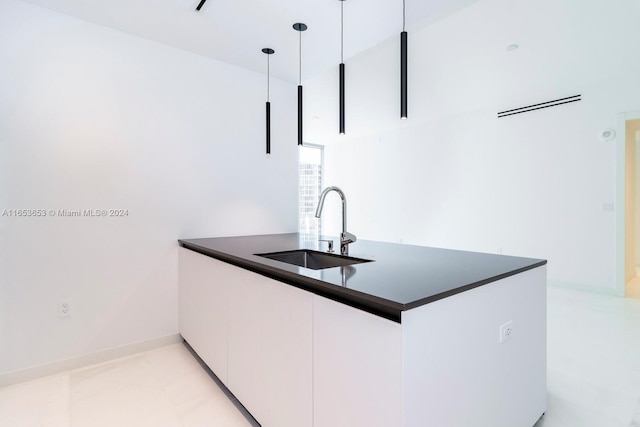 kitchen with hanging light fixtures, sink, kitchen peninsula, and white cabinetry