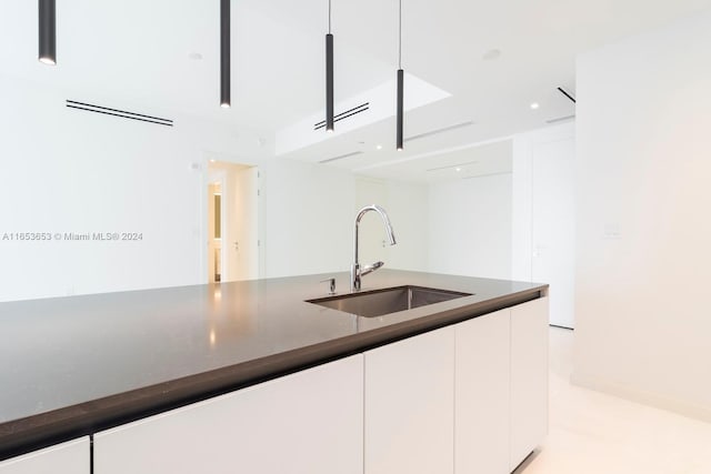 kitchen featuring white cabinets, dark stone countertops, and sink