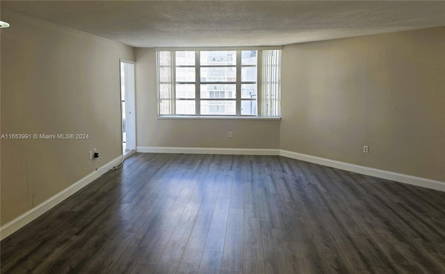 empty room with a textured ceiling and dark hardwood / wood-style floors