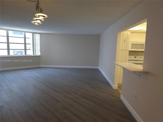 unfurnished room featuring baseboards and dark wood-style flooring