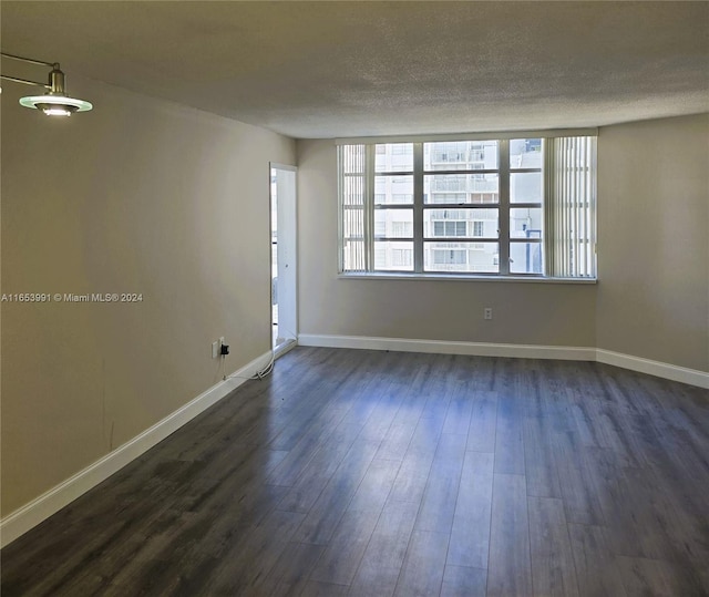 spare room featuring dark hardwood / wood-style floors and a textured ceiling