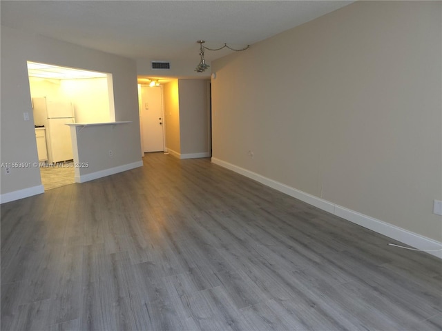 unfurnished living room featuring wood finished floors, visible vents, and baseboards