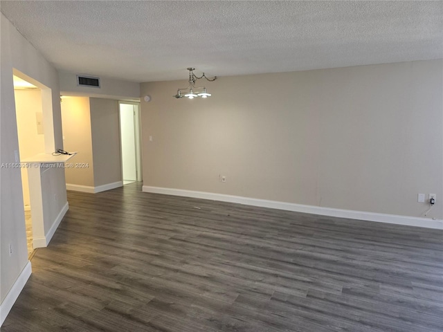 spare room featuring a textured ceiling and dark wood-type flooring