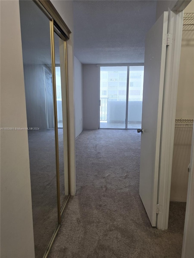 hall with a textured ceiling and dark carpet