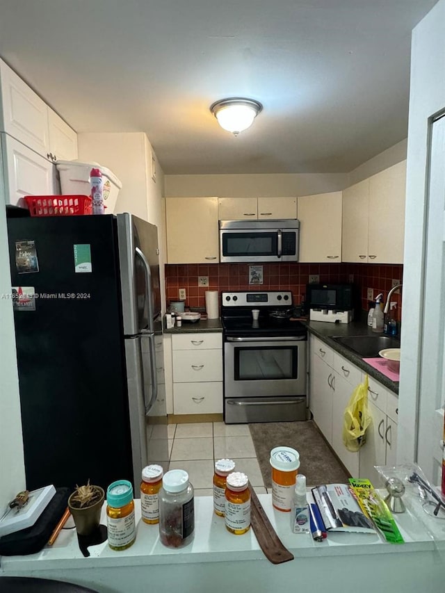 kitchen with appliances with stainless steel finishes, tasteful backsplash, light tile patterned floors, and sink