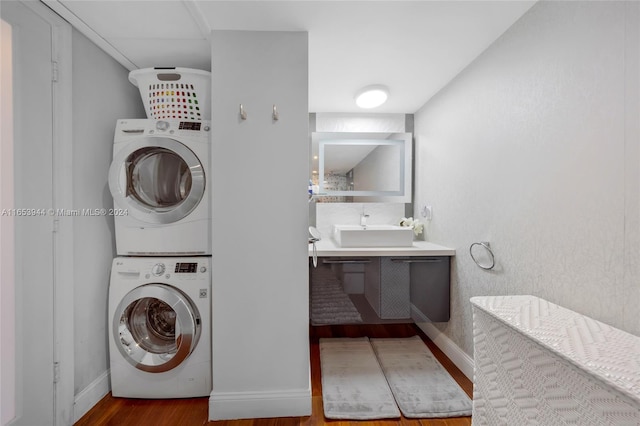 clothes washing area featuring wood-type flooring, sink, and stacked washer / drying machine