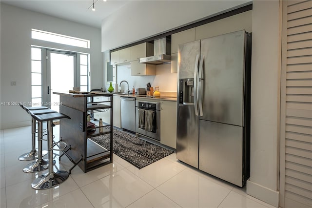 kitchen featuring wall chimney exhaust hood, light tile patterned floors, and stainless steel appliances