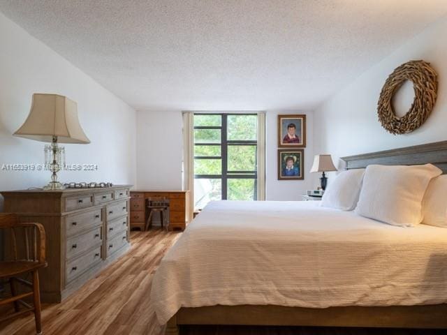 bedroom with light wood-type flooring and a textured ceiling