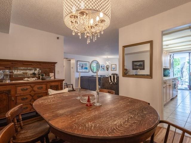 tiled dining room featuring an inviting chandelier and a textured ceiling