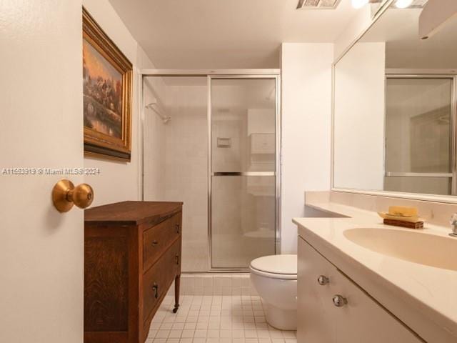 bathroom with tile patterned flooring, toilet, a shower with door, and vanity