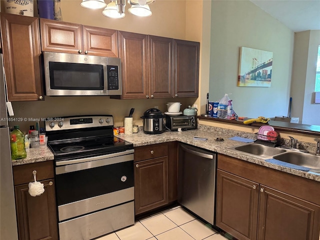 kitchen with light tile patterned floors, stainless steel appliances, a chandelier, and sink