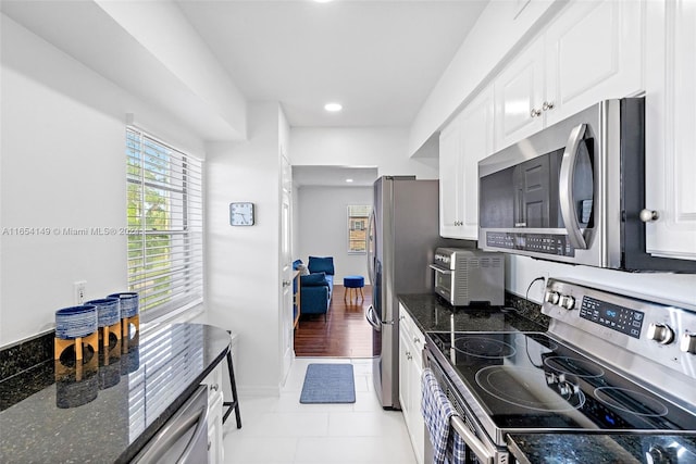 kitchen featuring dark stone countertops, appliances with stainless steel finishes, white cabinets, and light hardwood / wood-style floors