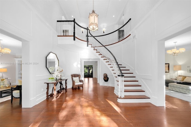 foyer entrance featuring a chandelier, dark wood-type flooring, and a towering ceiling