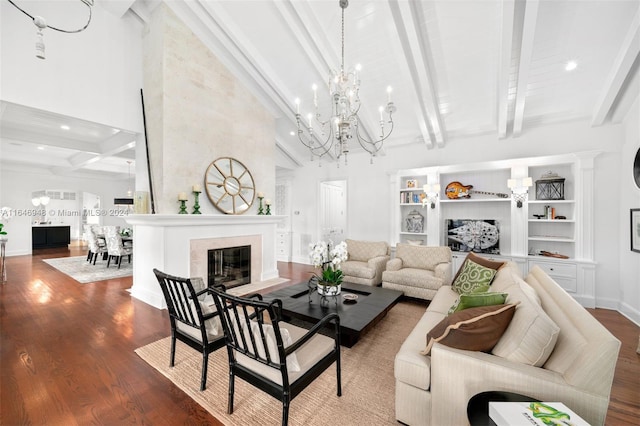 living room featuring a towering ceiling, a large fireplace, hardwood / wood-style floors, beam ceiling, and a notable chandelier