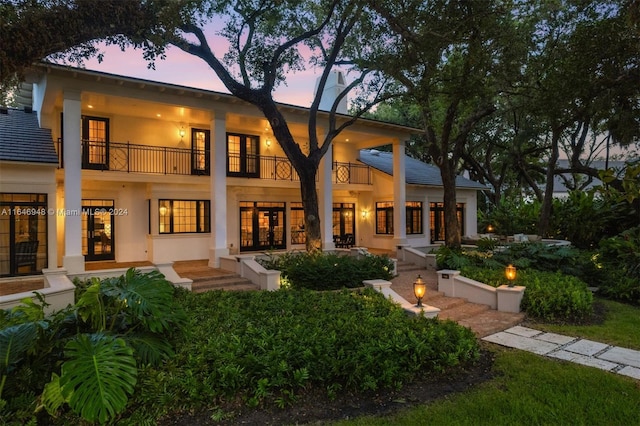 back house at dusk featuring a balcony