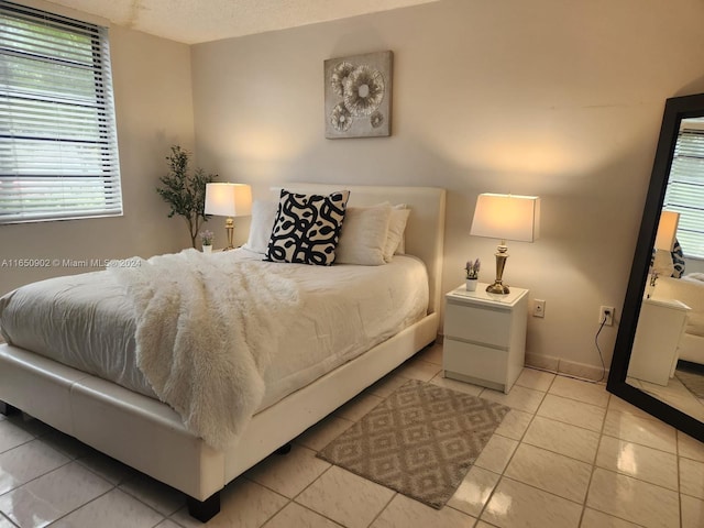 bedroom featuring multiple windows, a textured ceiling, and light tile patterned flooring