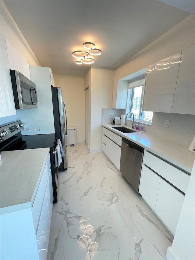 kitchen featuring appliances with stainless steel finishes, tasteful backsplash, sink, and white cabinets