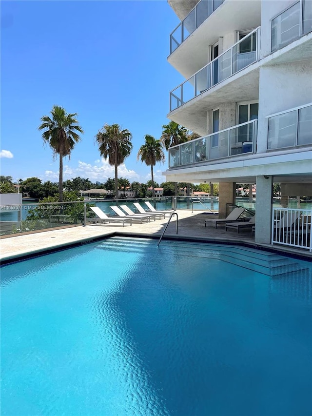 view of swimming pool featuring a water view and a patio area