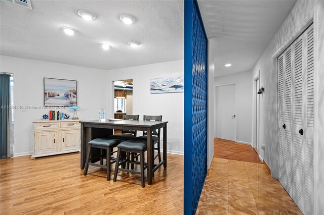 dining area with a textured ceiling and light hardwood / wood-style flooring