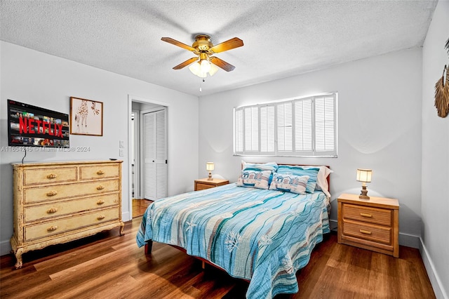 bedroom with a closet, a textured ceiling, ceiling fan, and dark hardwood / wood-style floors