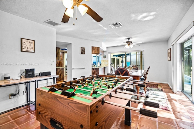 rec room featuring tile patterned flooring, ceiling fan, and a textured ceiling