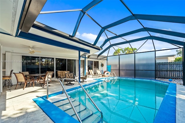 view of swimming pool with glass enclosure, ceiling fan, and a patio