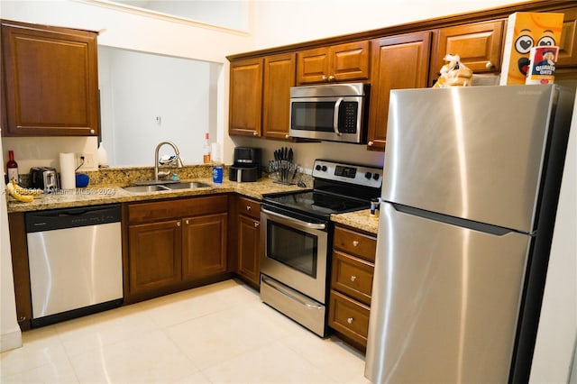 kitchen featuring light stone counters, stainless steel appliances, sink, and light tile patterned flooring