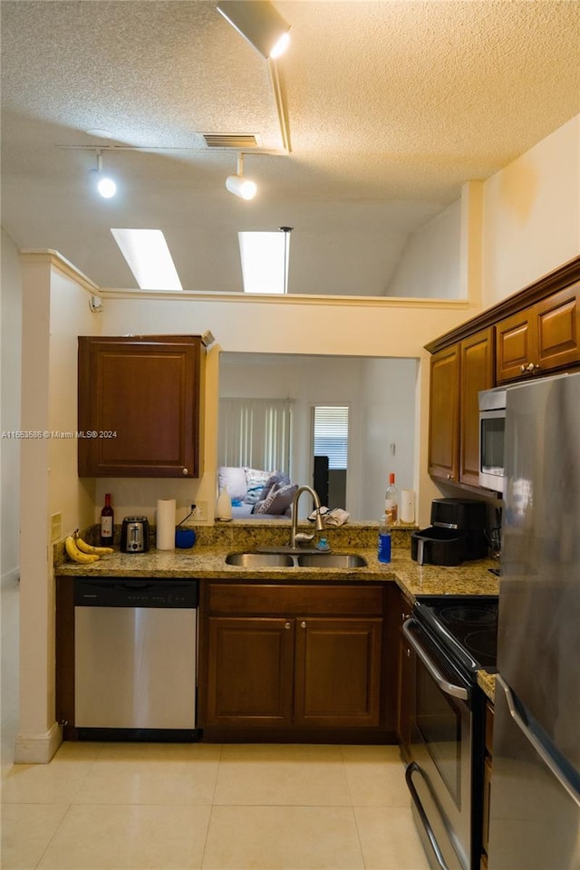 kitchen featuring a textured ceiling, stainless steel appliances, sink, and light tile patterned flooring