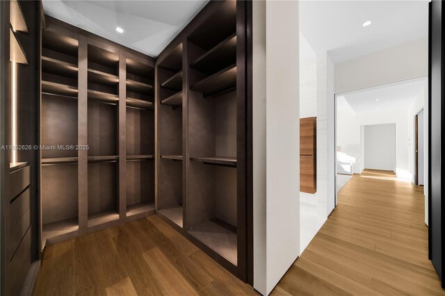 walk in closet with hardwood / wood-style floors and elevator