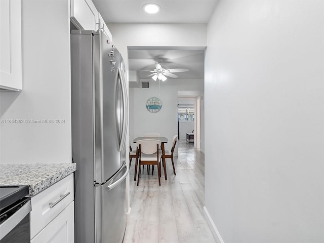 kitchen with white cabinets, ceiling fan, light hardwood / wood-style floors, and stainless steel refrigerator